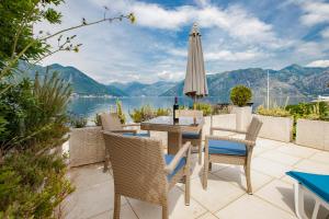 eine Terrasse mit einem Tisch, Stühlen und einem Sonnenschirm in der Unterkunft Apartments D&V in Kotor