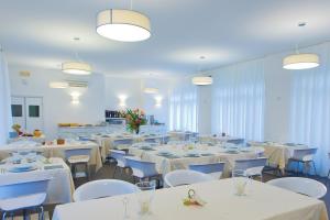 una sala da pranzo con tavoli e sedie bianchi di Hotel Mainè a Finale Ligure