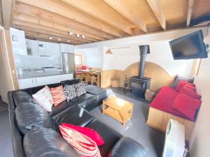 a living room with a black leather couch and a fireplace at Jagungal in Dinner Plain