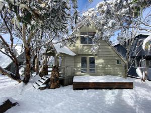 a house covered in snow with a bench in front at Jagungal in Dinner Plain