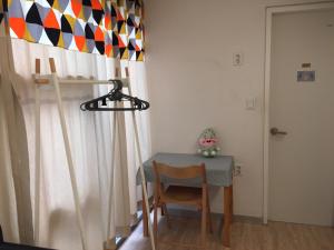 a table and a chair in a room with a curtain at Inside Busan Hostel in Busan