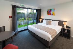 a bedroom with a large bed and a large window at Carnmore Hagley Park in Christchurch
