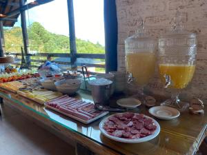 ein Buffet mit Fleisch und Getränken auf dem Tisch in der Unterkunft Pousada Cabana na Floresta - Monte Verde in Camanducaia