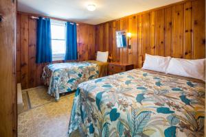 sypialnia z 2 łóżkami i drewnianymi ścianami w obiekcie Oceana Cottages w mieście North Truro