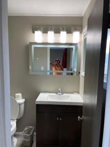 a man taking a picture of a bathroom with a sink at Timberly Motel in Gaylord