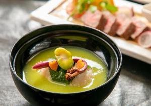 a black bowl of soup with vegetables and meat at Yufuin Onsen Hinoharu Ryokan in Yufu