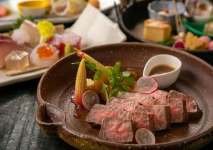 a plate of food with meat and vegetables on a table at Yufuin Onsen Hinoharu Ryokan in Yufu
