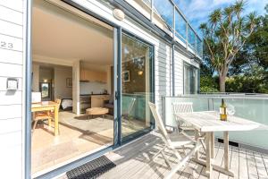 a sliding glass door leading to a patio with a table and chairs at Villa Haven - Waiheke Escapes in Palm Beach