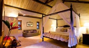 a bedroom with a canopy bed and a couch at Lakaz Chamarel Exclusive Lodge in Chamarel