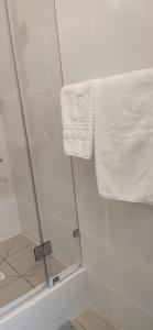um chuveiro com uma porta de vidro e uma toalha em Sulo Aksai Hotel em Aksay