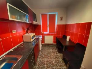 a small red kitchen with a sink and a microwave at Apartament Sira in Sulina +7 photos