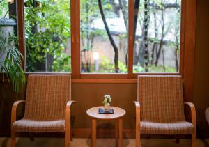 two chairs and a table in front of a window at Yufuin Onsen Hinoharu Ryokan in Yufu
