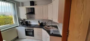 cocina con armarios blancos, fregadero y ventana en Ferienwohnung Lewitztor, en Plate