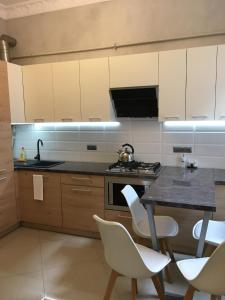 a kitchen with white chairs and a table with a sink at APARTMENT ON CENTRE LVIV in Lviv