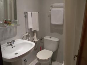 a bathroom with a white toilet and a sink at Hotel Solymar in Bricia