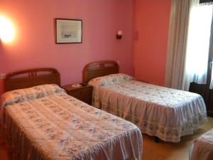 two beds in a room with red walls at Hotel Solymar in Bricia