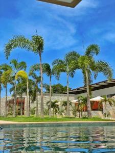 a pool with palm trees in front of a building at Resort Île de Pipa Flat in Pipa