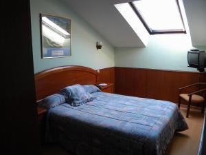 a bedroom with a bed with a blue comforter and a window at Hotel Solymar in Bricia