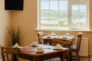 una sala da pranzo con tavoli, sedie e una finestra di Seaview Heights a Dingle