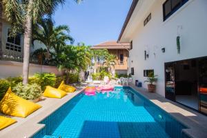 Una piscina con almohadas rosas y amarillas y un resort. en Luxury Pool Villa 4 BR 900M beach 1.5 KM downtown, en Pattaya South