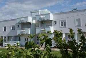 a white building with trees in front of it at Apartments Toka in Petrcane