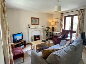 een woonkamer met een bank en een open haard bij Derrybrook Cottage, Twin or Superking, Seven Springs Cottages in Cheltenham