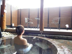uma mulher sentada numa piscina num edifício em ペンション木もれ日 em Ito