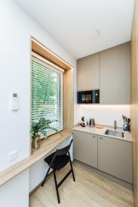 eine Küche mit einem Schreibtisch, einem Fenster und einem Waschbecken in der Unterkunft River city apartments No 4 by URBAN RENT in Kaunas