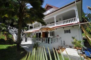 a white house with a palm tree in front of it at Chrisent Residence in Port Glaud