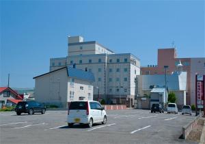 uma carrinha branca estacionada num parque de estacionamento com um edifício em Grand Hotel Fujika em Nayoro