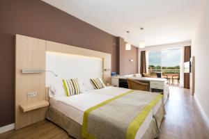 Schlafzimmer mit einem großen Bett, einem Schreibtisch und einem Fenster in der Unterkunft Hotel Mariant Park in Sa Coma