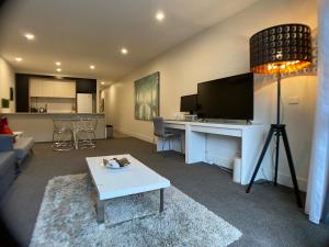 un soggiorno con divano e scrivania con TV di The Gallery Luxe 1 BR Executive Apartment in the heart of Braddon Wine Secure Parking WiFi a Canberra