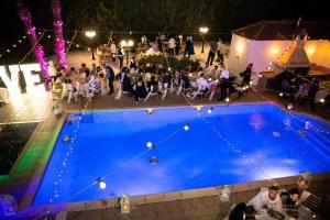 un grupo de personas sentadas alrededor de una piscina en una fiesta en Mansion 12 en Lárnaca