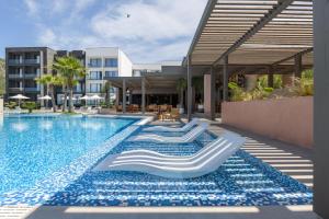 a swimming pool with lounge chairs next to a building at Miamar Luxury Hotel & Spa in Himare