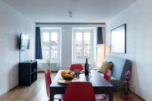 ein Wohnzimmer mit einem Tisch und roten Stühlen in der Unterkunft HITrental Chapel Bridge Apartments in Luzern