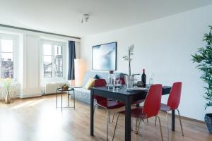 a living room with a dining room table and red chairs at HITrental Chapel Bridge Apartments in Luzern