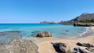 a beach with rocks and the ocean on a clear day at Doma Apartments in Falasarna