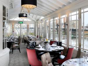a dining room with tables and chairs and windows at Macdonald Compleat Angler in Marlow