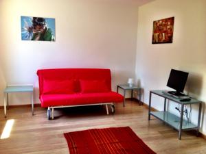 sala de estar con sofá rojo y ordenador portátil en Casa Romea, en Cividale del Friuli