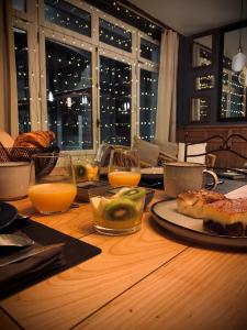 - une table en bois avec de la nourriture et des verres de jus d'orange dans l'établissement L'AccrocheCoeur, à Saint-Malo
