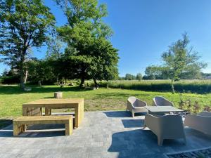 un patio con una mesa de madera, bancos y un campo en Cense de Lalouette en Saint-Ghislain