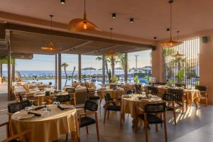 a restaurant with tables and chairs and windows at Miamar Luxury Hotel & Spa in Himare