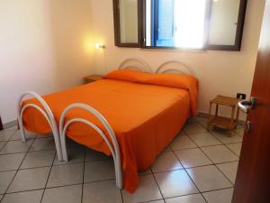 a bed with an orange comforter in a room at Le villette Blu di Torre Pali di Salentoinvacanza COM in Torre Pali 