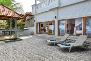 un patio con 2 sillas y una cama en una casa en Villa Spice House Inn Downstair, en Lovina