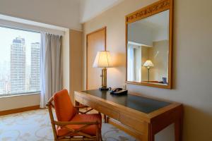 Habitación de hotel con escritorio y espejo en Shangri-La Beihai, en Beihai