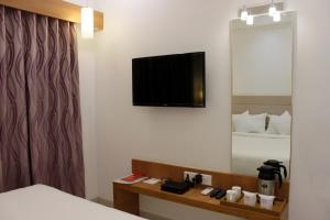アーメダバードにあるHotel Ashray Innのベッドと壁にテレビが備わるホテルルームです。