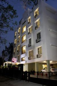 Hotel Ashray Inn في أحمد آباد: مبنى أبيض فيه سيارة متوقفة أمامه