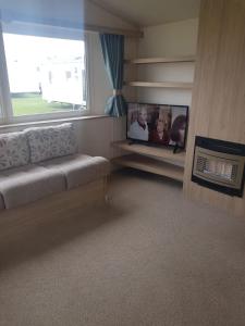 uma sala de estar com um sofá e uma janela em TSCaravan, Haven, Golden Sands em Mablethorpe