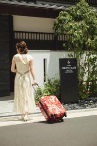 GRAND BASE -Nagoya Chiyokura- في ناغويا: امرأة في ثوب تسحب حقيبة حمراء