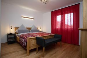 1 dormitorio con 1 cama con cortina roja y silla en Ferienwohnung FühlDichWohl, en Übersee